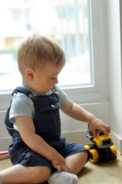 istock A small child plays with a toy car while sitting by the window 2159991146