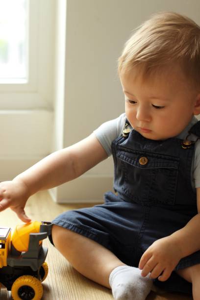 istock A small child plays with a toy car while sitting by the window 2159991268