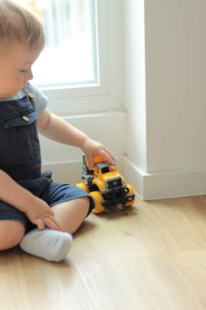 istock A small child plays with a toy car while sitting by the window 2159991355