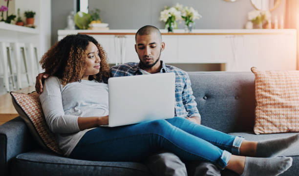 istock A relaxed couple on sofa watching movie on laptop or browsing internet for a romantic afternoon indoors. Casual, young and in love boyfriend and girlfriend bonding while searching the web on laptop 2159994553