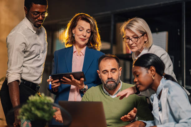 istock Mature executive with laptop collaborating with interracial team at office 2160002834