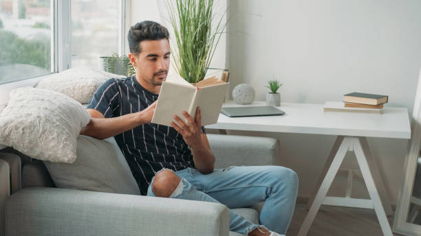 istock Book research education reading man couch home 2160003376