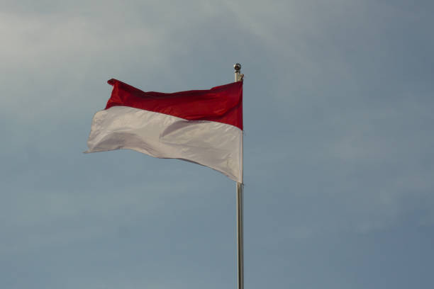 istock A red and white flag on an iron pole against a blue sky background 2160004768