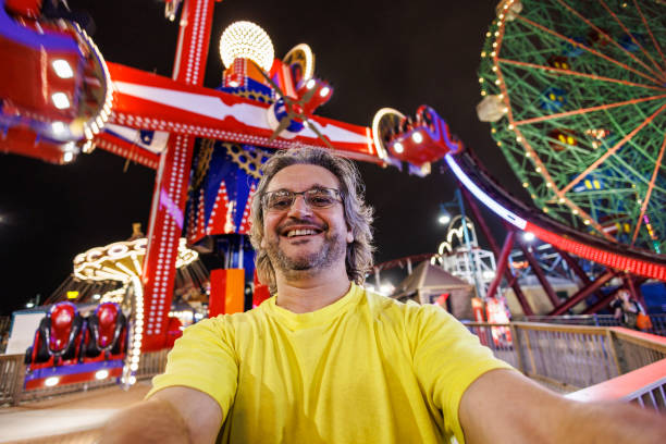 istock Smiling bearded man taking selfies in illuminated amusement park at night 2160005414