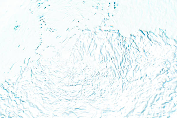 Blue water with ripples on the surface. Defocus blurred transparent blue colored clear calm water surface texture with splashes and bubbles. Water waves with shining pattern texture background.