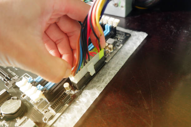 Man's hands plugging in the ATX power plug of a computer motherboard.