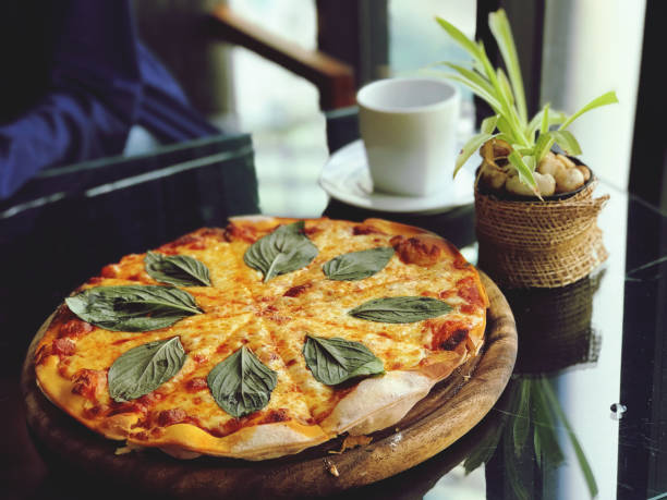 Pizza with mozzarella cheese and basil leaves on wooden plate.