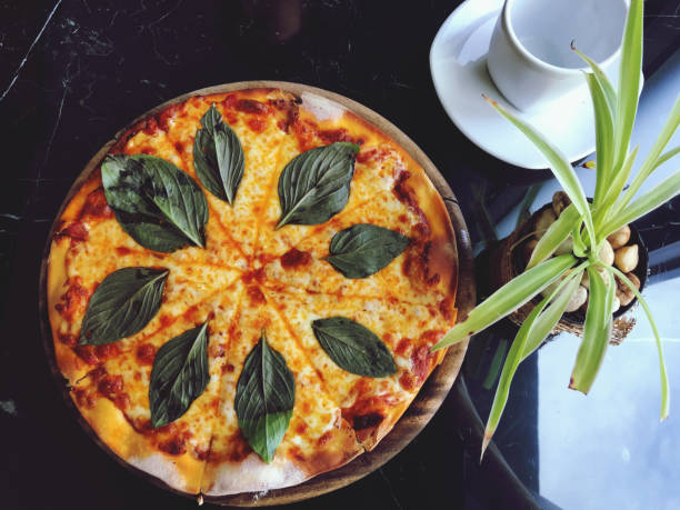 Pizza with mozzarella cheese, tomatoes and basil leaves.