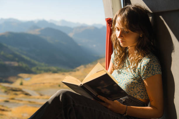 istock Woman reading book in camper van in mountains 2160018526