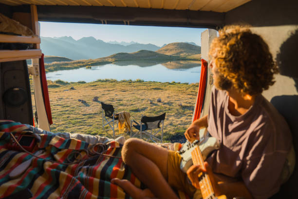 istock Man with guitar in camper van in mountains 2160018599