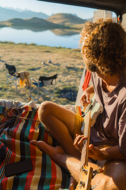 istock Man with guitar in camper van in mountains 2160018600