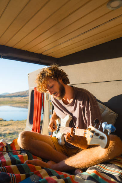 istock Man with guitar in camper van in mountains 2160018601