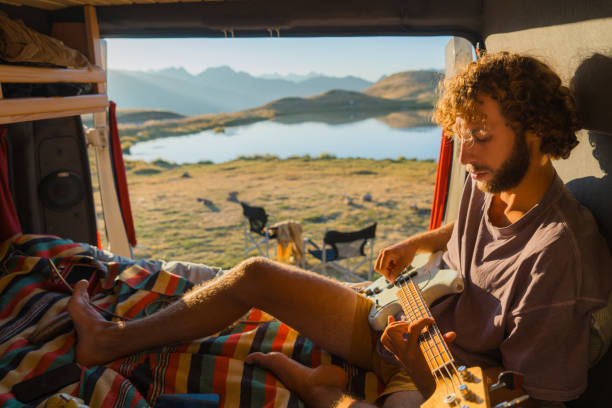 istock Man with guitar in camper van in mountains 2160018611