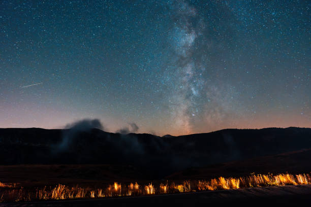 Milky way above the road illuminated by car headlights at night
