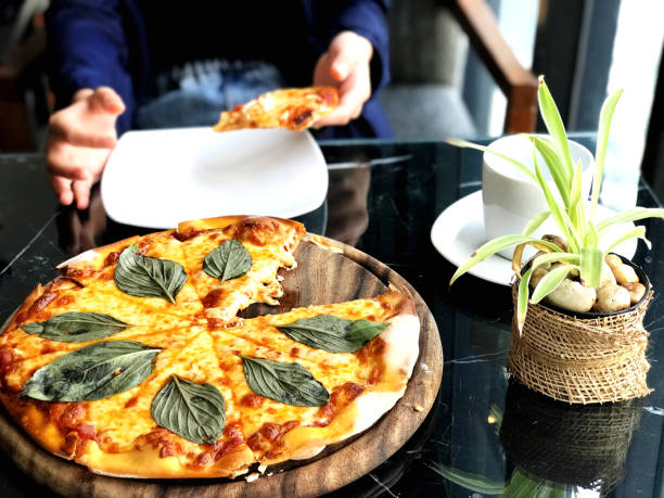 Pizza with mozzarella cheese and basil leaves on wooden plate.