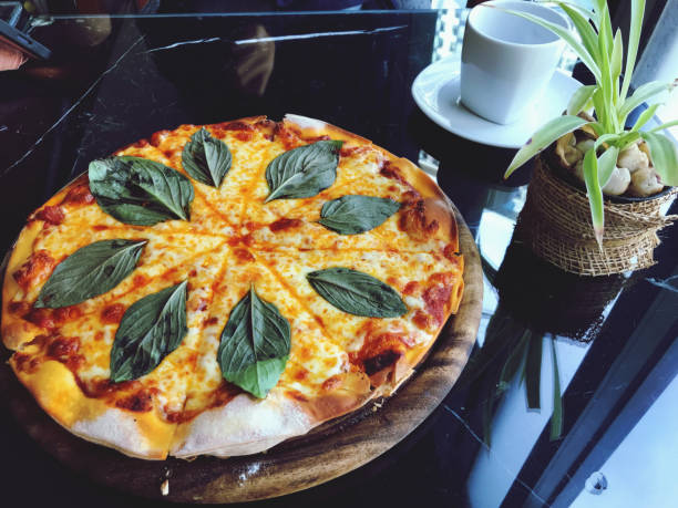 Pizza with mozzarella cheese and basil leaves on wooden plate.