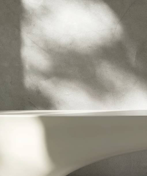 istock Blank cream white countertop podium counter, soft beautiful dappled sunlight, leaf shadow on polished concrete cement wall 2160020508