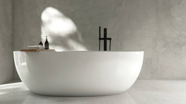 istock White freestanding ceramic bathtub, black shower head, faucet, in sunlight, tree leaf shadow on polished cement concrete wall 2160020529