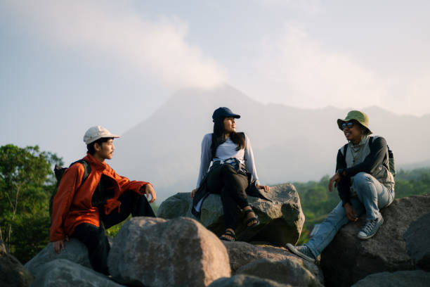 istock Three Friends Hanging Out Resting on Large Rocks with Merapi Mountain at the Background 2160021372