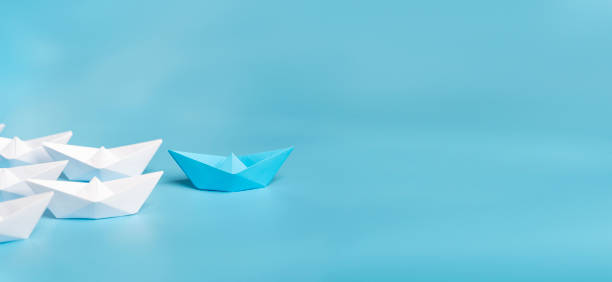 istock Leadership concept using blue paper ship among white. 2160021587