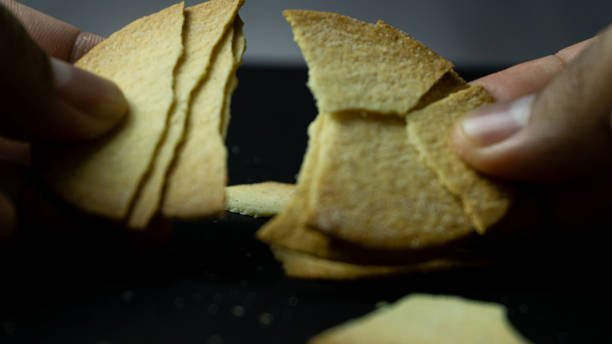 istock Baked chips being broken by hand on a black background table 2160026441