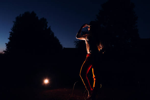 Rear view of a teenager man looking at the city lights at night. He is wearing a casual green t-shirt.