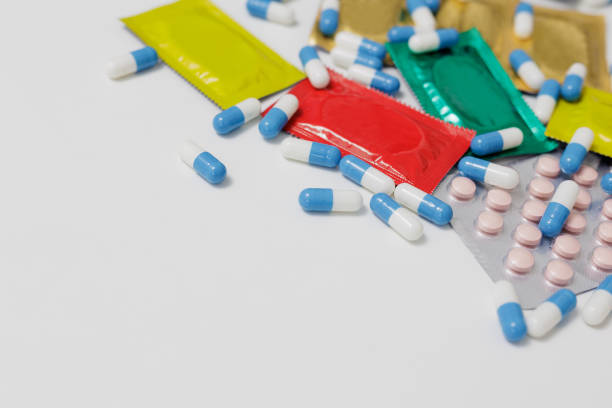 istock Protection concept - red, yellow, green condoms and blue pills with copyspace 2160033122