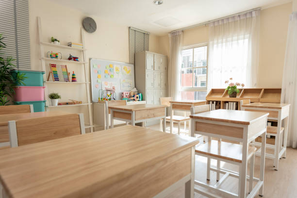Shot of empty classroom with chairs under desks in elementary. School during vacation or holidays, A teaching classroom without students during a term break or the end of semester in kindergarten.