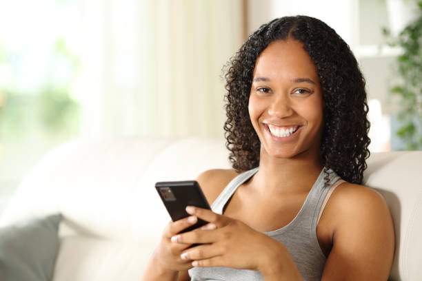 istock Happy black woman holding smartphone looking at camera 2160039037