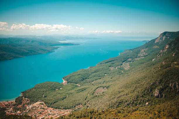 The image showcases the town's picturesque landscape, featuring traditional architecture, lush greenery, and the serene coastline of the Aegean Sea