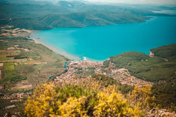 The image showcases the town's picturesque landscape, featuring traditional architecture, lush greenery, and the serene coastline of the Aegean Sea