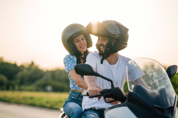 heureux jeune couple roulant sur une moto sur la route dans la nature - moto photos et images de collection