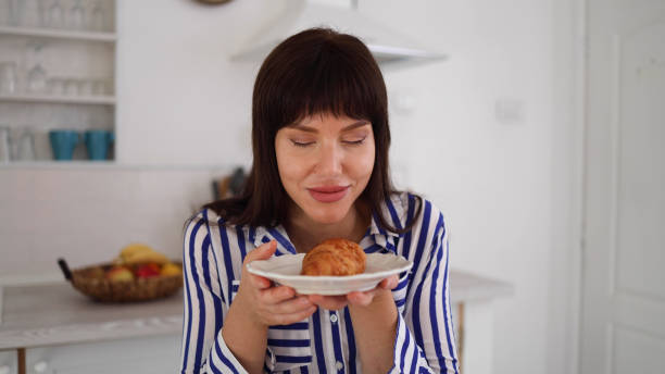 istock Young woman eating a croissant for breakfast 2160052086