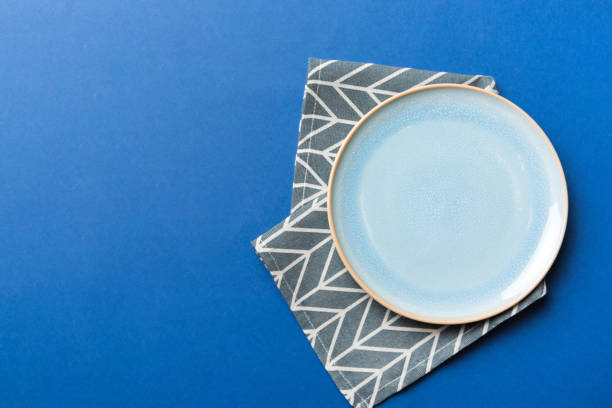 istock Top view on colored background empty round blue plate on tablecloth for food. Empty dish on napkin with space for your design 2160052933