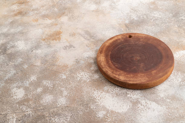 istock Empty round wooden cutting board on brown concrete. Side view, copy space 2160056387