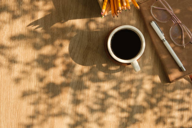 istock A cup of coffee, eyeglasses and notebook on wooden table. Top view with copy space. 2160059319