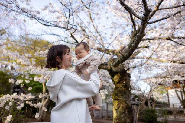 istock Mother holding her little baby under cherry blossoms 2160059504