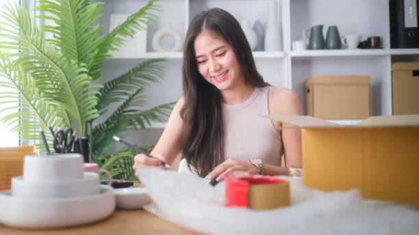 istock Small business entrepreneur writing order in notebook while sitting in pottery shop with handmade ceramic products. 2160059997
