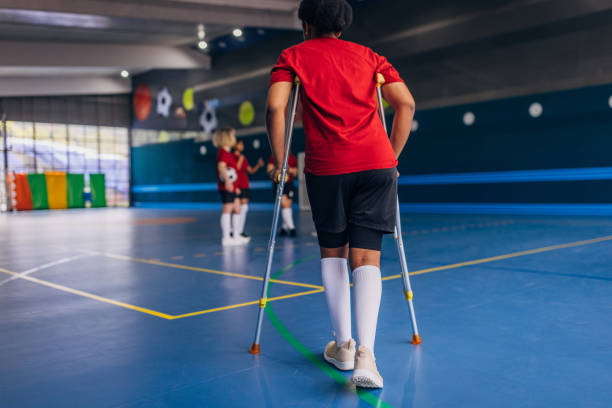 istock Player on crutches walks towards a sports team 2160062609