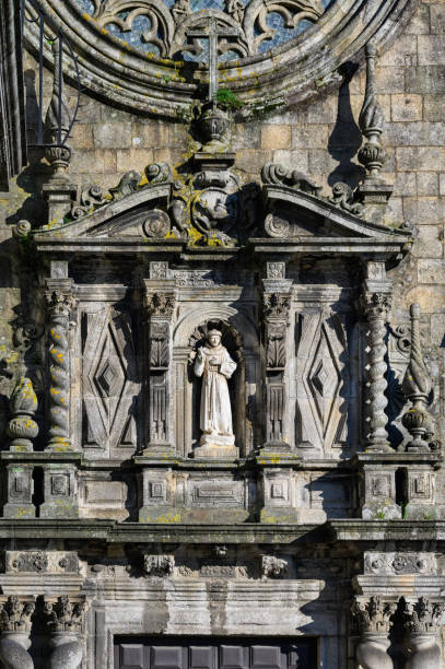 Santiago de Compostela, Spain - Mai 21, 2024 - Two angels holding an iron cross at the roof of the portal of Santiago de Compostela cathedral, Spain