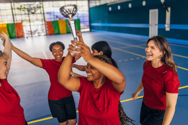 istock Team celebrating victory with trophy held high in air 2160066003