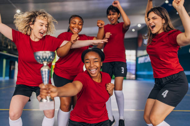 istock Team energetically celebrating victory holding trophy high 2160066241