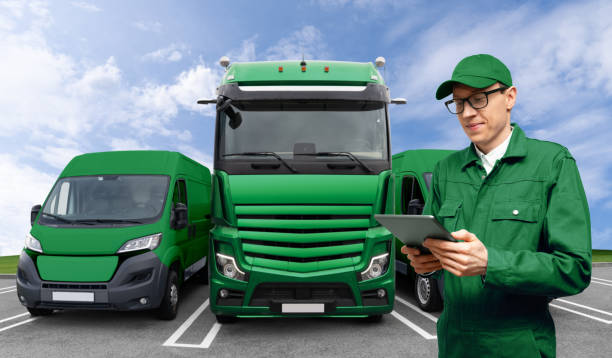 istock Manager with digital tablet next to green vans and truck 2160066336
