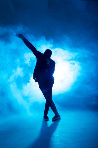 istock Male break dancer performs on blue neon stage his expressive dance, light flare 2160066419