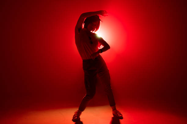 istock Stylish female dancer standing in dancing pose on red studio background 2160066460