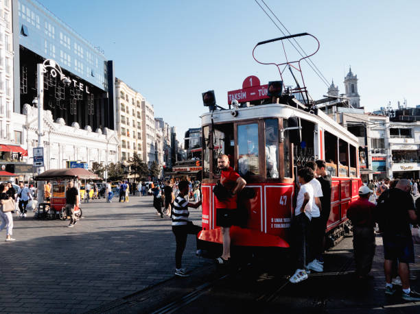 Istanbul, Turkey - August 25, 2023: People hang from a traditional tram in Istanbul.