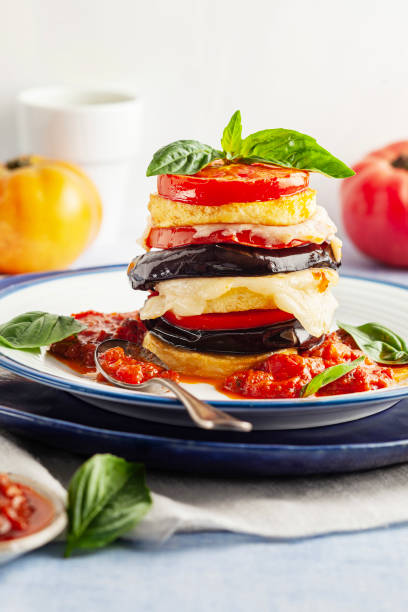 Ratatouille Tower. Fresh vegetarian healthy grilled vegetables on white plate. Sliced ​​stack eggplant baked tomatoes and potato with cheese. Eggplant Parmigiana