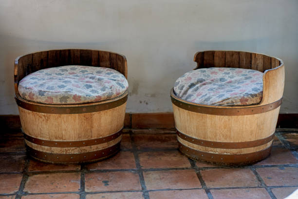 2 old low round wooden stools with dirty cushions inside a warehouse