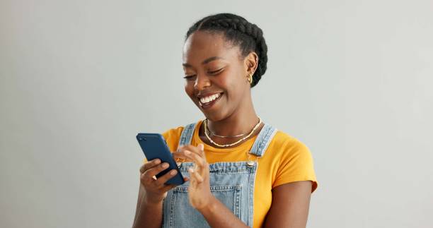 istock Woman, happy and typing in studio on smartphone, browsing and reading text message on mobile app on background. Communication, social media update and scrolling with internet, website and email 2160078653
