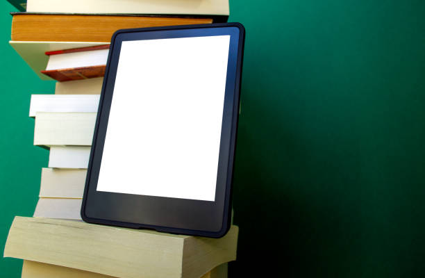 an electronic book next to a stack of paper books on a dark green background